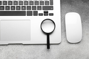 Laptop, computer mouse and magnifier on table. Internet search concept
