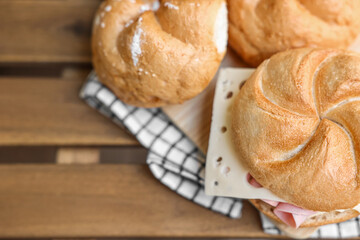 Kaiser rolls with ham and cheese on wooden board