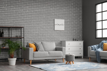 Stylish interior of living room with modern furniture near grey brick wall