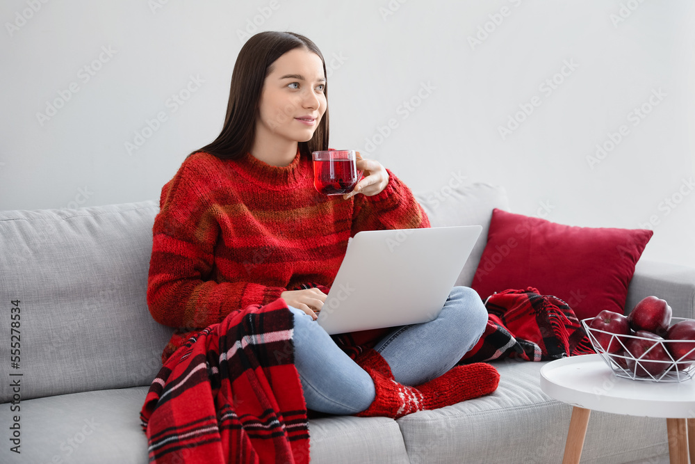 Sticker young woman with cup of tea and laptop sitting on sofa at home