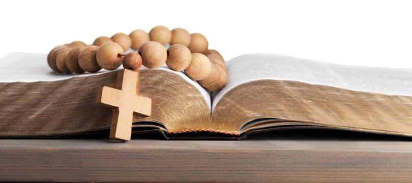 Rosary beads on open bible on wooden table