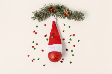Composition with Santa hat, Christmas ball, sequins and coniferous branch on light background