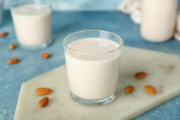 Board with glass of healthy almond milk on color background, closeup