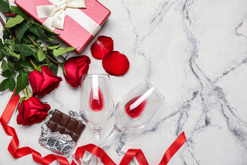 Fototapeta na wymiar Glasses of wine, roses, gift and chocolate on grunge background. Valentine's Day celebration
