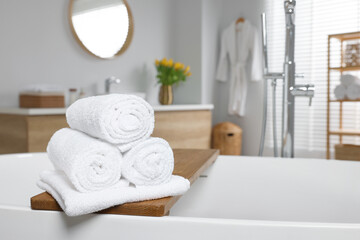 Fototapeta na wymiar Rolled white towels on tub in bathroom. Space for text