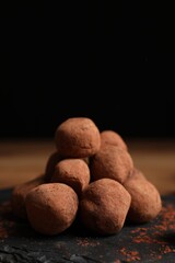 Tasty chocolate truffles powdered with cacao on slate board