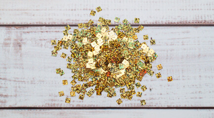 Pile of many golden sequins on white wooden table, top view