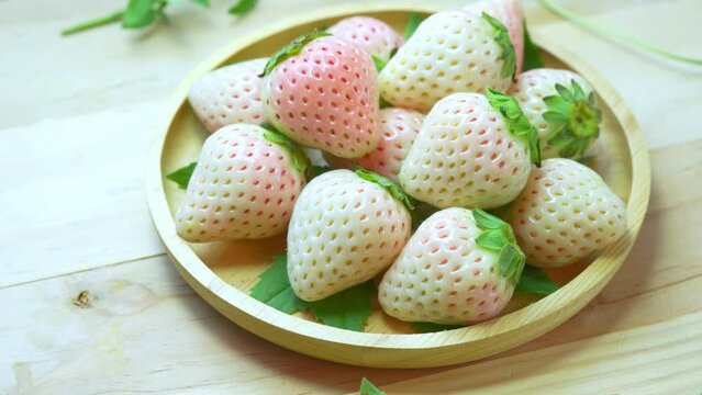 Fresh pink snow strawberry in wooden plate on wooden background, White and Pink snow Strawberries on wooden Background.