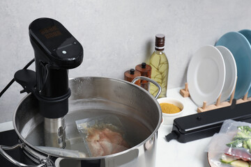 Thermal immersion circulator and vacuum packed meat in pot on table. Sous vide cooking