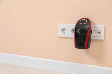 Modern compact electric heater charging from socket indoors, space for text