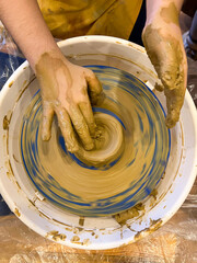 Serious young boy student of pottery class is molding clay on spinning potter's wheel, learning traditional craft. Serious child is concentrated on work, getting new experience.
