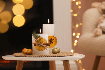 Beautiful candles decorated with dry orange slices and cinnamon sticks on white table indoors....