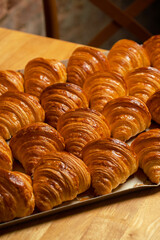 Freshly baked crispy golden croissants on a metal tray. Group of french croissants.