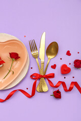Table setting for Valentine's Day with golden cutlery, bow and hearts on lilac background