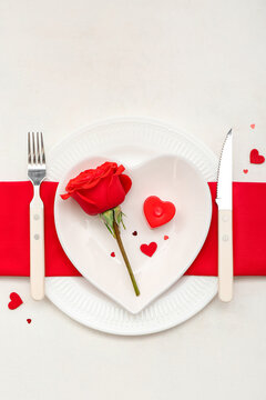 Table setting for Valentine's Day with rose and hearts on white background