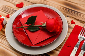 Table setting for Valentine's Day with rose and envelope on wooden background, closeup