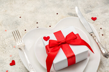 Table setting for Valentine's Day with gift and hearts on grunge background, closeup