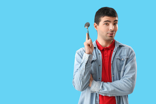 Young man with tablespoon on blue background