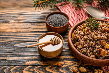 Bowl of Kutya with Christmas branch and ingredients on dark wooden background