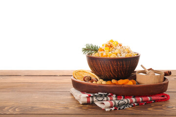 Board with bowl of rice Kutya, ingredients and napkin on table against white background