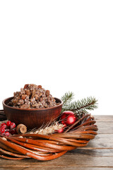 Bowl of Kutya and Christmas wreath on table against white background
