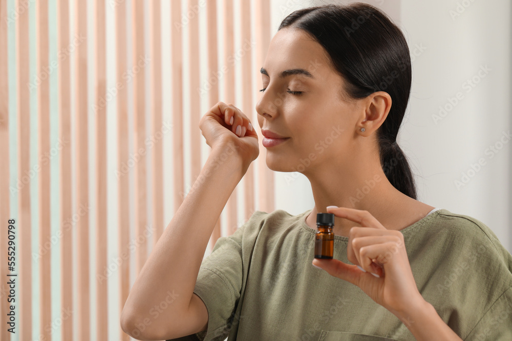 Canvas Prints Young woman smelling essential oil on wrist indoors