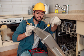 Service man repairing dishwasher in modern kitchen. Maintenance and household assistance concept 