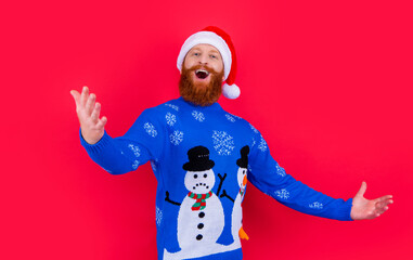 caucasian singing man in christmas sweater and santa hat isolated on red background.