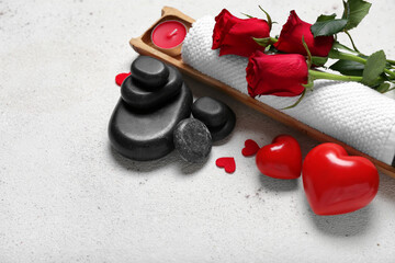 Beautiful spa composition for Valentine's Day with flowers, towel, hearts and stones on light background