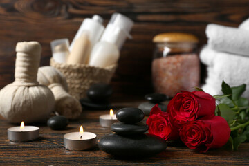 Beautiful spa composition for Valentine's Day with stones, candles and rose flowers on wooden background