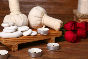 Fototapeta na wymiar Beautiful spa composition for Valentine's Day with stones, candles, rose flowers and herbal bags on wooden background