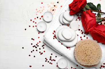 Obraz na płótnie Canvas Beautiful spa composition for Valentine's Day with rose flowers, brush, towel and stones on white wooden background