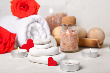 Fototapeta na wymiar Beautiful spa composition for Valentine's Day with candles and stones on light background