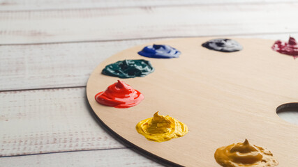 Artist's palette with samples of colorful paints on white wooden table, closeup. Space for text