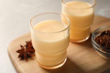 Glasses of delicious eggnog with anise on grey marble table, closeup