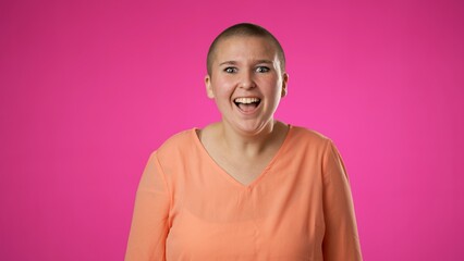 Portrait of surprised excited young gender fluid non binary woman 20s celebrate great success, winner, YES, WOW, isolated on pink background.