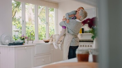 Family, kitchen and grandmother lifting girl enjoying weekend, holiday and quality time together at home. Love, affection and happy grandma carrying young child in arms for bonding in family home - Powered by Adobe