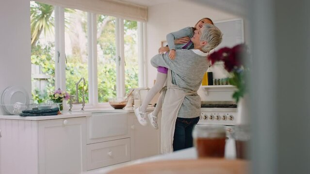 Family, kitchen and grandmother lifting girl enjoying weekend, holiday and quality time together at home. Love, affection and happy grandma carrying young child in arms for bonding in family home