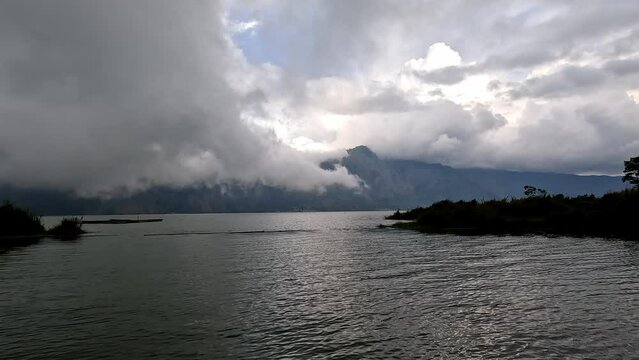 Vapor clouds rolling over lake in Kintamani, Bali, in evening dusk.