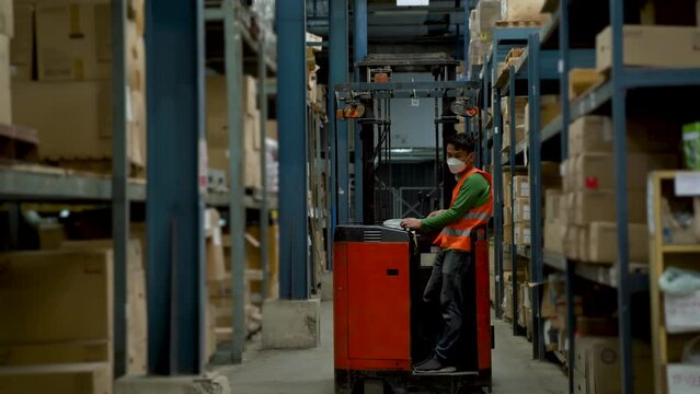 4K, Male employees who drive forklift  goods in warehouse, car is driving forklift  along way, in order to carry goods as needed in car, He wore a safety vest while driving inside a large warehouse.