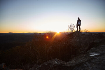 Man standing looking out over mountains on sunset