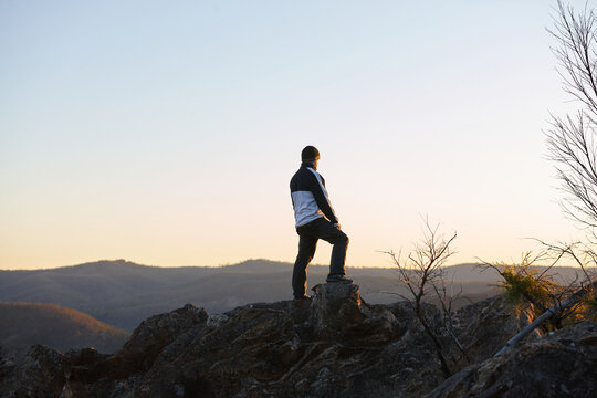 Man standing looking out over mountains on sunset