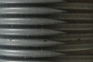 Close up section of a corrugated iron rainwater tank. Old Australian rainwater tank. Curved corrugated metal rain water tank with shadows cast by side-lighting from the setting sun.