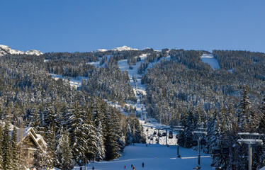 Snow covered mountains panorama - snowboarders and skiers ride on slopes and ski lifts. Ski resort...