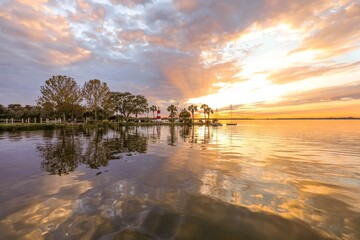Fototapeta na wymiar Brilliant sunset shining through clouds over Lake Dora in Florida