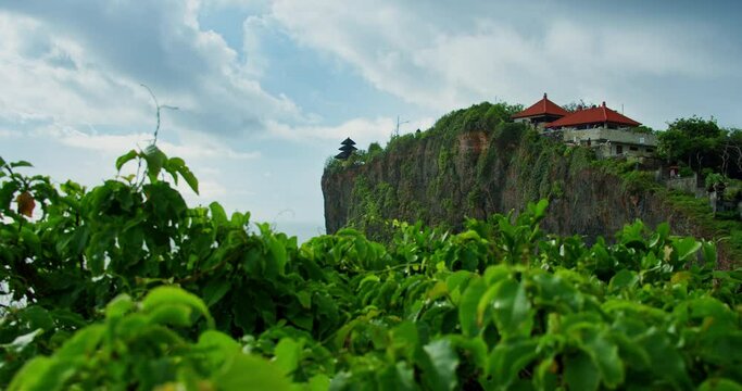 Pura Luhur Uluwatu temple Bali Indonesia. Beautiful huge cliff with exotic tropical plants. Famous historic religious balinese monument. Rocky coastline. Tourist attraction.