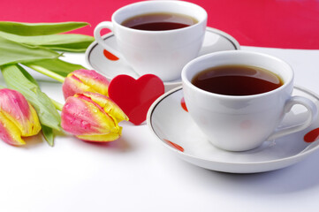 Two cups of tea, a red heart and a bouquet of red tulips. Tea for two.