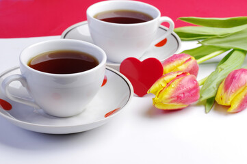 Two cups of tea, a red heart and a bouquet of red tulips. Tea for two.