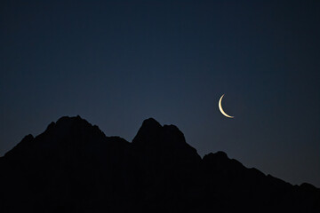 Waning moon over Alaska mountains in the pre-dawn sky.