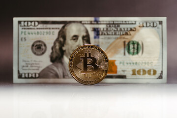 bitcoin coin with 100 dollar paper bill in the background